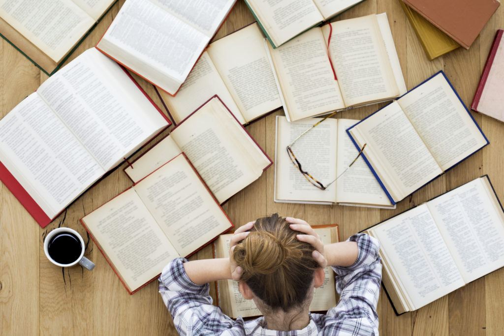 girl sitting at table with books spread out trying to decide college major