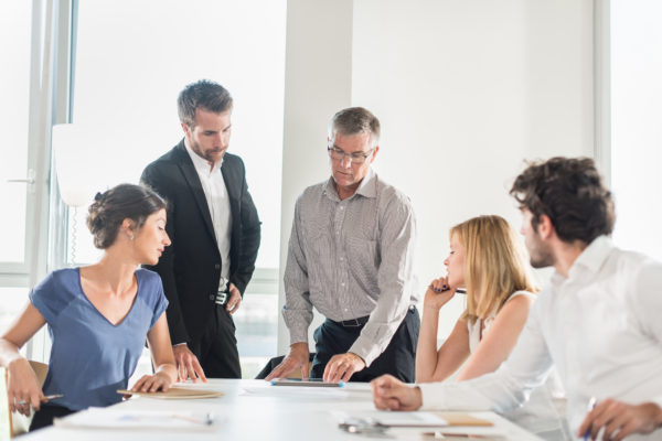 group of colleagues meeting around a conference room table. how to manage your boss