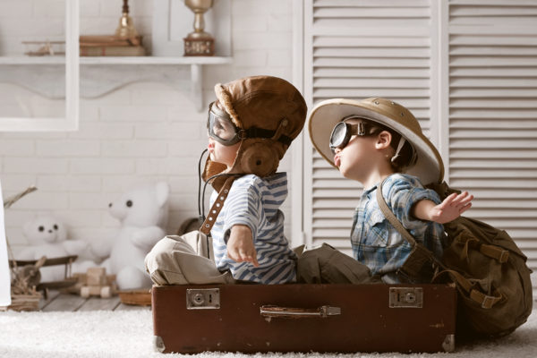 childhood best friends playing dress up and airplane with toys