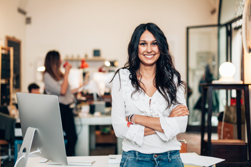 woman standing in front of office, proud of launching a company