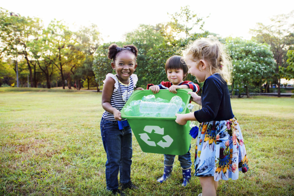 three kids filling a recycling bin demonstrating volunteer opportunities for kids