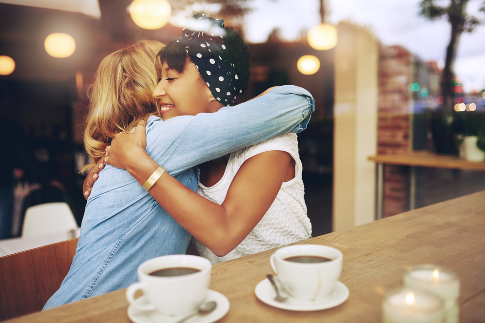 Two friends hugging and having coffee