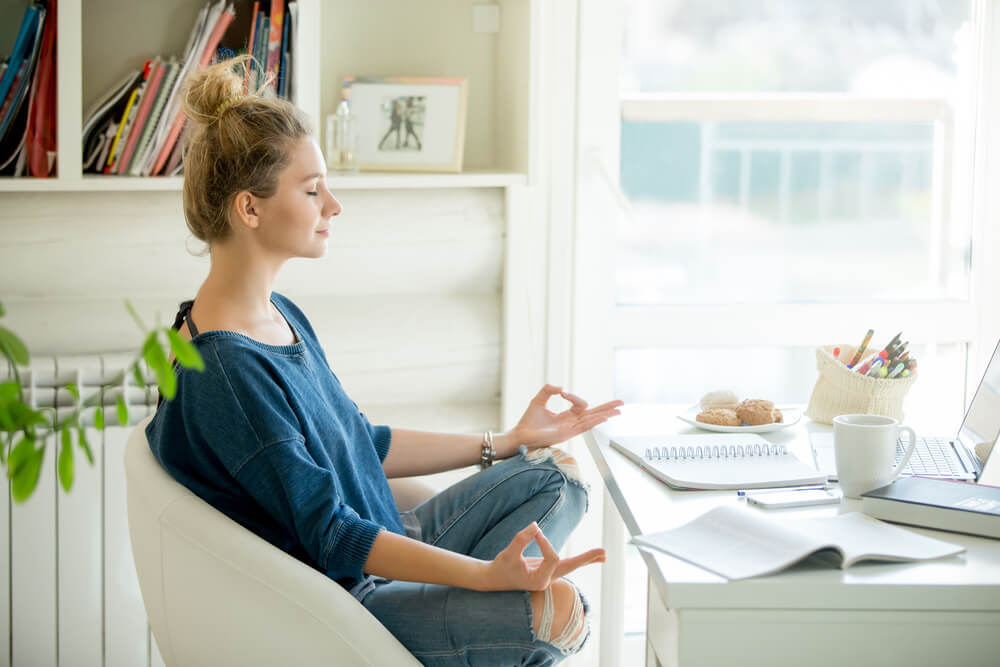 girl practicing meditation at her desk in order to manage stress levels