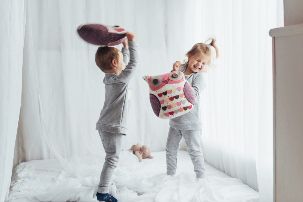 young siblings having a pillow fight