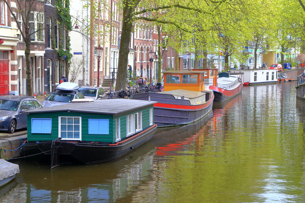 Traditional wooden boats along a canal in the Jordaan neighborhood in Amsterdam - a travel bucket list destination