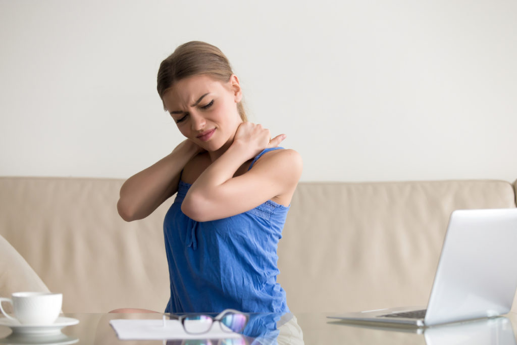 girl holding her neck in pain, needing a posture corrector device
