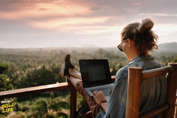 Some woman working on her laptop while looking out over nature