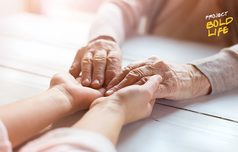 A pair of elderly hands holding younger hands