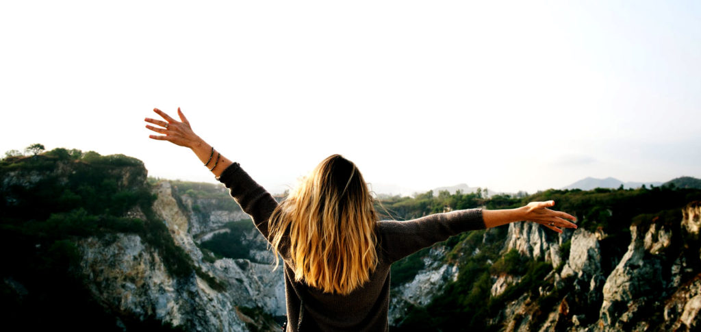 Girl overlooking beautiful view with hands in air embracing bad days that can be good for you