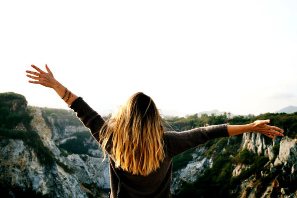 Girl overlooking beautiful view with hands in air embracing bad days that can be good for you