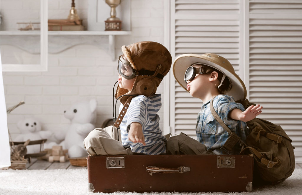 childhood best friends playing dress up and airplane with toys
