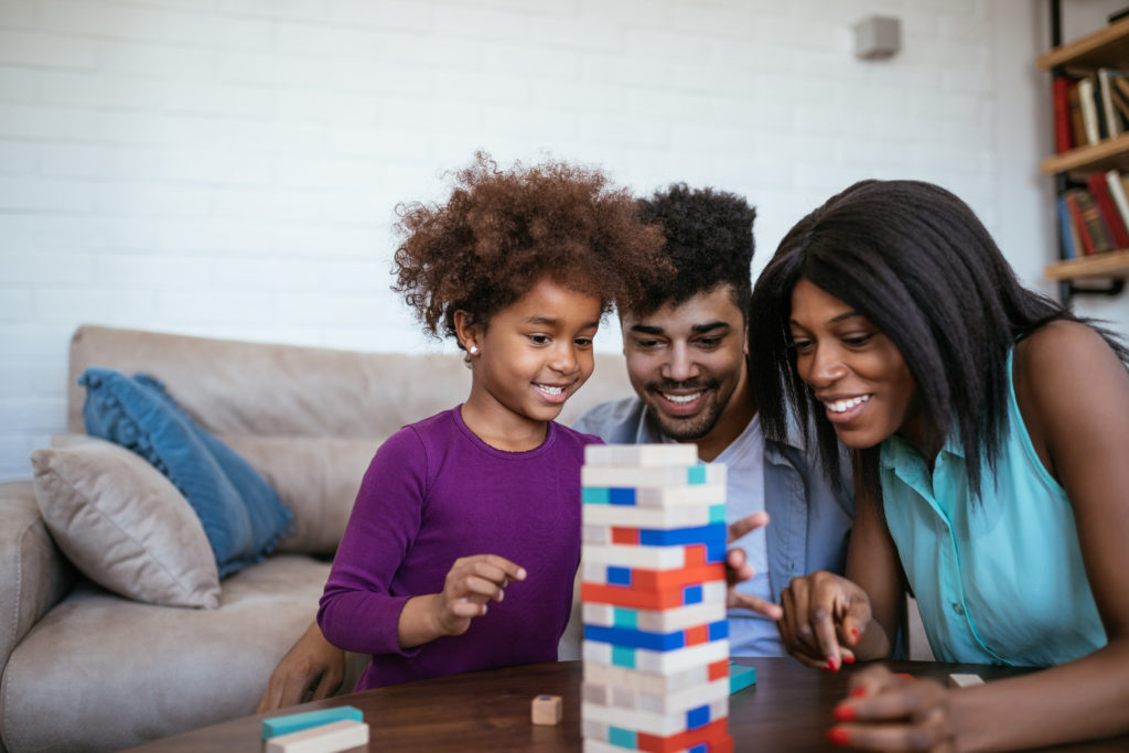 family of 3 playing jenga at the coffee table - family game night