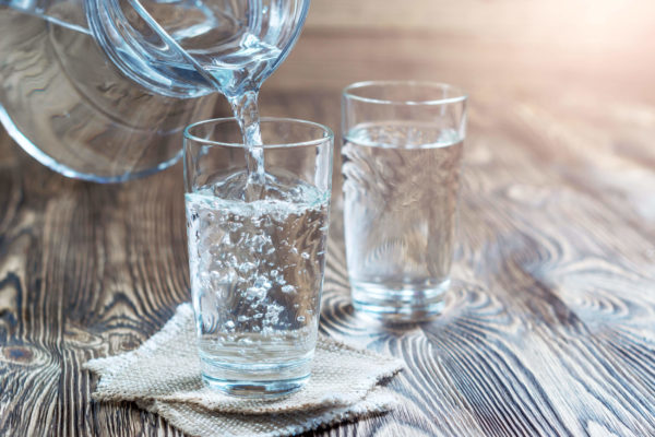 pitcher pouring into two glasses to achieve proper hydration