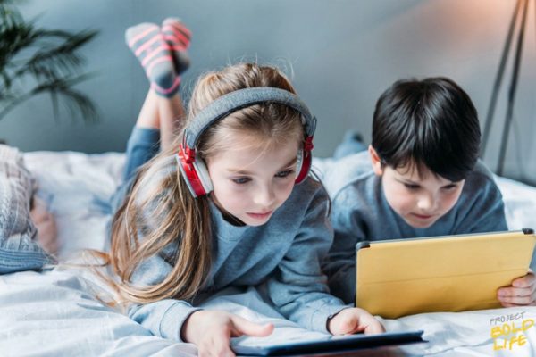 two kids laying side by side playing on their ipads - kids and technology