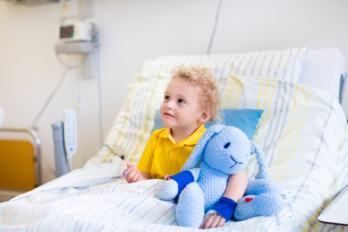 young boy in hospital bed holding a toy provided by toy drive