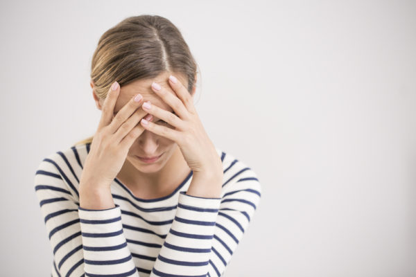 woman holding her head in her hands - difference between headache and migraine