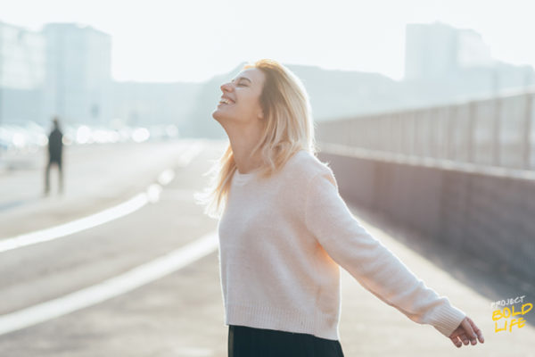 woman looking carefree with her arms open looking at the sky - living in the present