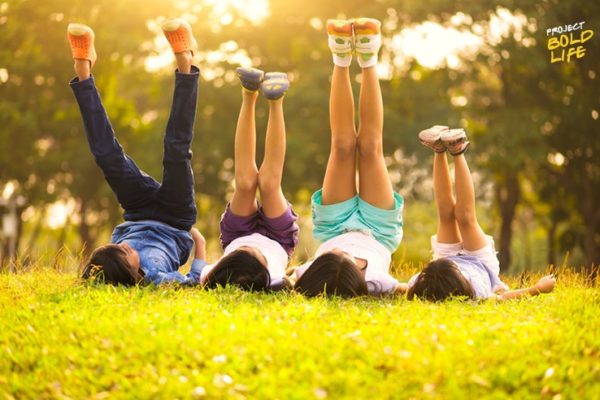 kids laying in the grass with their legs in the air - childlike wonder