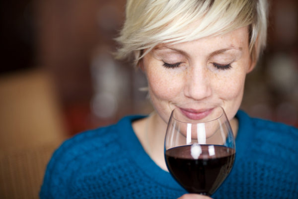 woman with her eyes closed smelling a big glass of wine