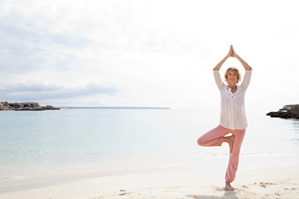 woman balancing on one leg on the beach - representing benefits of stem cells for health