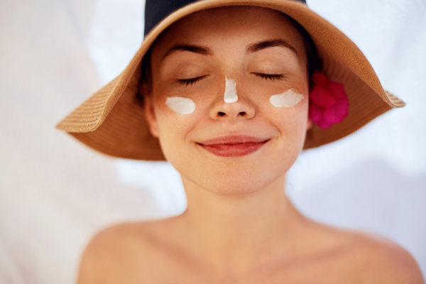 girl in a hat wearing skin cream