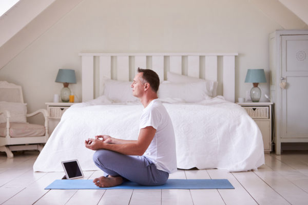 man meditating in his bedroom with the assistance of a mindfulness app