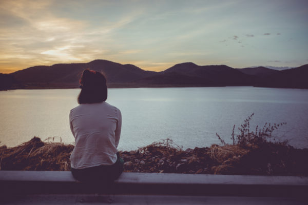 girl sitting and looking out over a lake