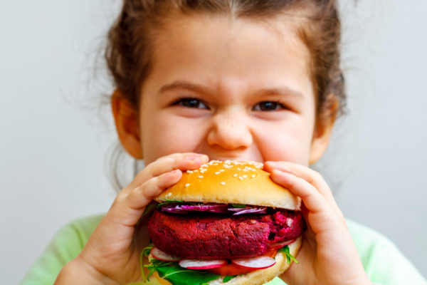 child raised vegan eating a vegan burger