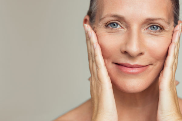 a woman pushing back the wrinkles on her face