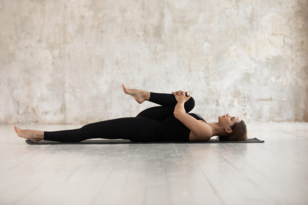woman doing stretching exercises on yoga mat for chronic pain relief