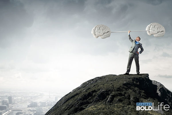 A person standing atop a mountain lifting a barbell with enlarged brains