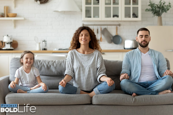 A family meditating on a couch