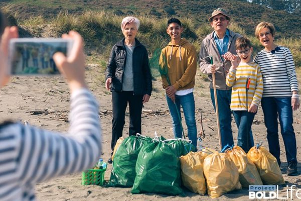 A family happily collecting trash on the beach