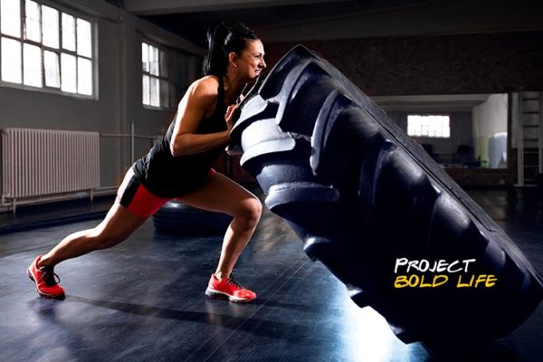 A woman flipping a tire in a hard workout