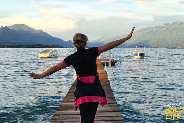 A woman on a dock trying to fly like a plane