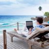 Some dude working on his laptop on the beach