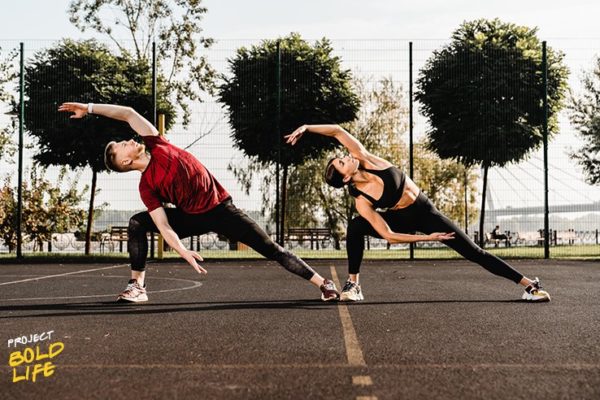 A couple doing side bends on a basketball court