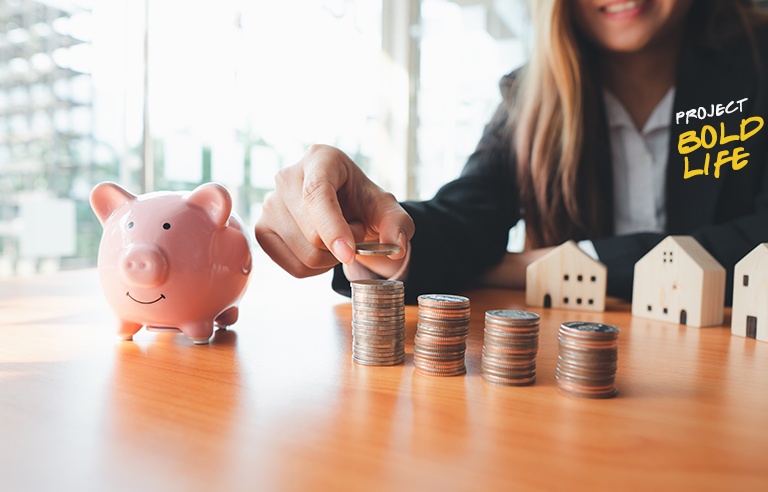 Someone saving their coins with a pink piggy bank