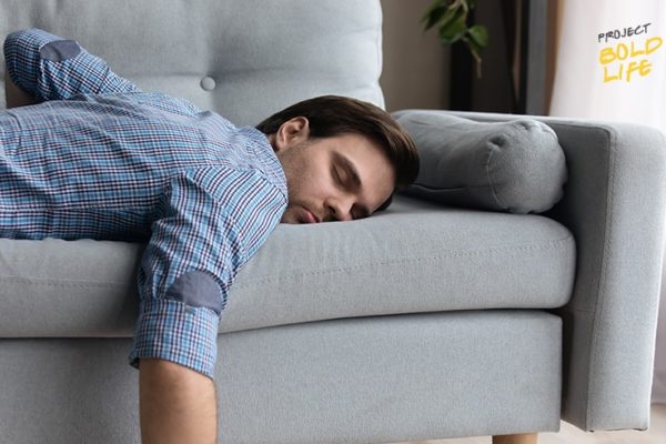 A dude fatigued and passed out on a couch